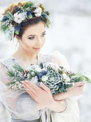 Portrait of a beautiful bride with a bouquet. Wedding ceremony in winter.
