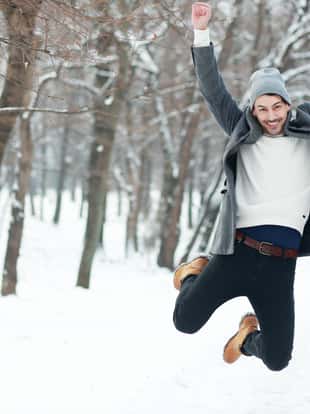 happy young man on winter park jumping have joy