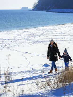 Mother with little son walking on snowy beach, Poland