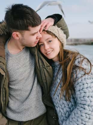 young smiling couple embracing on winter sea shore
