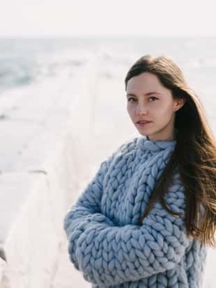 beautiful young girl in merino wool sweater on winter quay at the sea