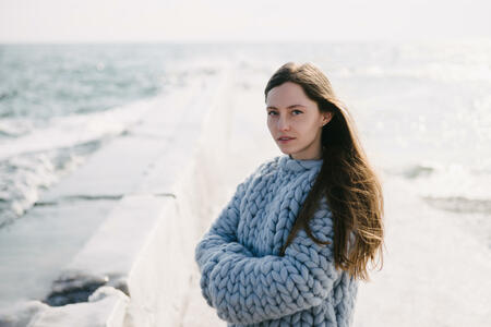 beautiful young girl in merino wool sweater on winter quay at the sea