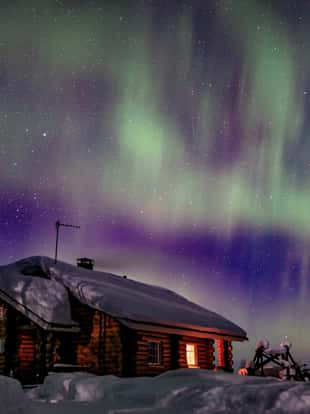 Polar arctic Northern lights Aurora Borealis activity over wooden cabin in winter Finland, Lapland