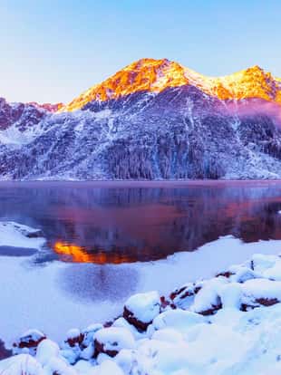Winter Alps. Italian Alps with snow at sunrise. Mountains illuminated with rising sun. Picturesque winter mountain landscape.