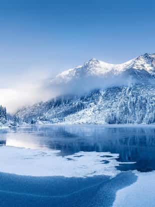 Winter panoramic landscape with scenic frozen mountain lake and clear blue sky. Alps, Switzerland.
