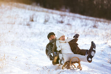 Beautiful senior woman and man on sledge having fun in sunny winter nature.
