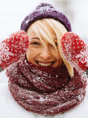Cheerful young woman si smiling at the camera and showing her gloves, winter funny atmosphere.