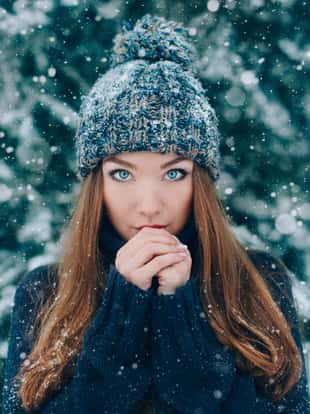 Christmas portrait of beautiful girl in hat with snow