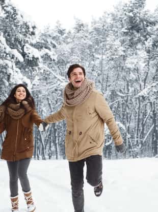 Xmas Morning. Excited Couple Running Through Snowy Winter Forest Holding Hands Having Fun Outside. Panorama, Copy Space
