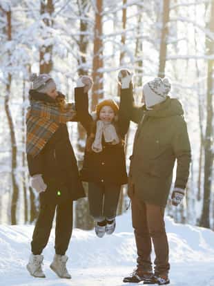 Full length portrait of happy family having fun in beautiful winter forest, copy space