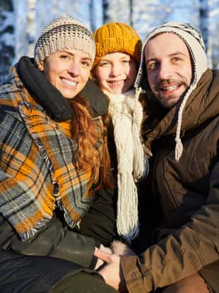 Portrait of loving family posing looking at camera in beautiful winter forest, copy space