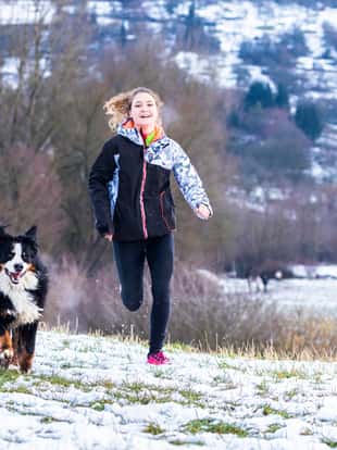junge Frau joggt mit Hund (Bernhardiner) in verschneiter Winterlandschaft, Schorndorf, Baden-Württemberg, Deutschland