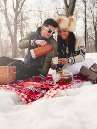 Group of millenial young adult friends enjoying wintertime and in a snow filled park