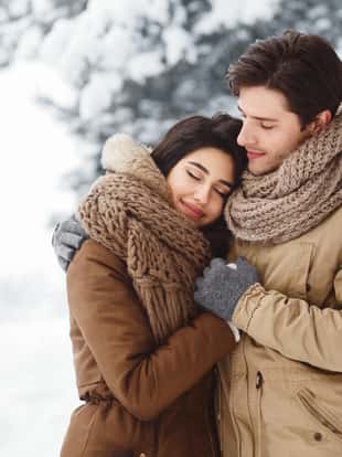Peaceful Couple Of Lovers Embracing Standing In Snowy Winter Forest In The Morning. Winter Date Concept.
