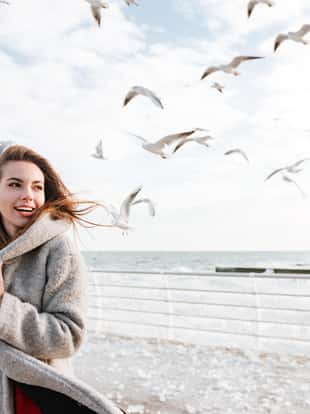 Smiling beautiful young woman standing on pier in winter