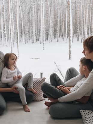 The family is sitting at the window and looking at the winter forest. Good New Year spirit. Morning in pajamas.