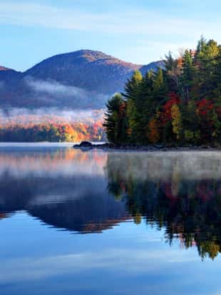 Early morning autumn in the Green Mountain National Forest in Vermont. Photo taken on a calm foggy colorful morning during the peak autumn foliage season. Vermont's beautiful fall foliage ranks with the best in New England bringing out some of the most colorful foliage in the United States