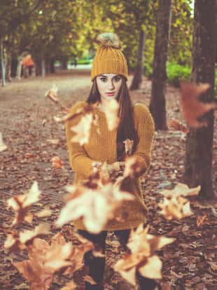 beautiful young  woman throwing leaves in autumn