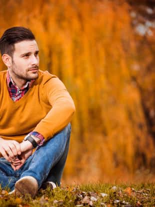Young handsome man posing in autumn park.