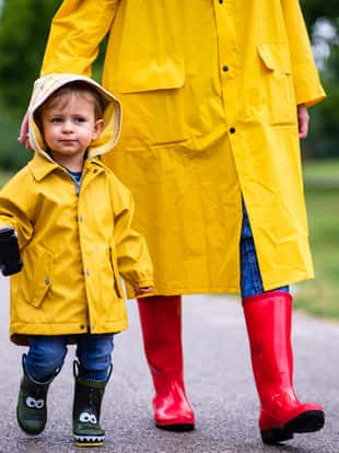 Mother and toddler child, boy, playing in the rain, wearing boots and raincoats