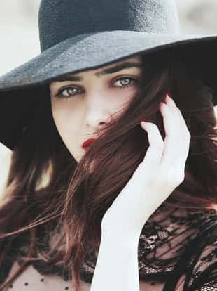 Young brunette woman wearing hat outdoors