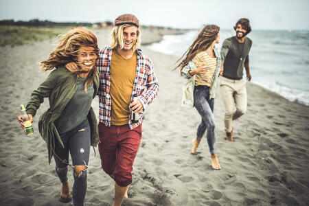 Two happy couples having fun while spending an autumn day on the beach. Focus is on couple in the foreground looking at camera.