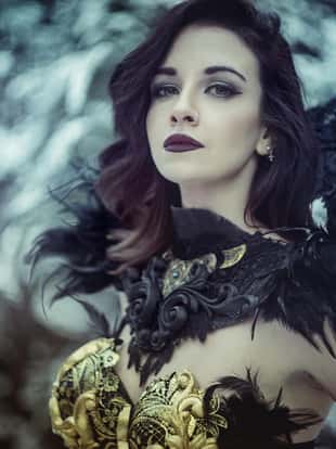Queen, Beautiful brunette woman with gothic dress made in gold and black threads. It is in a snowy forest in winter. fantasy concept