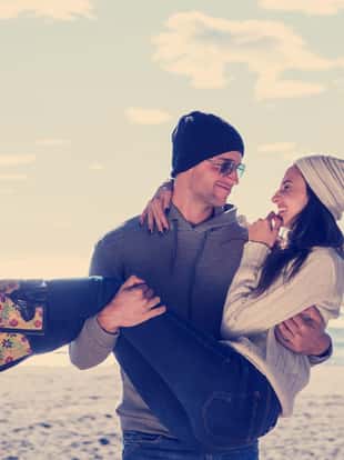 Happy couple enyojing time together on beach during autumn day