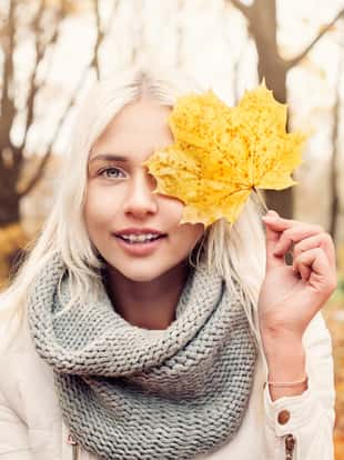 Beautiful Autumn Woman with Yellow Autumn Leaves on Fall Nature Background