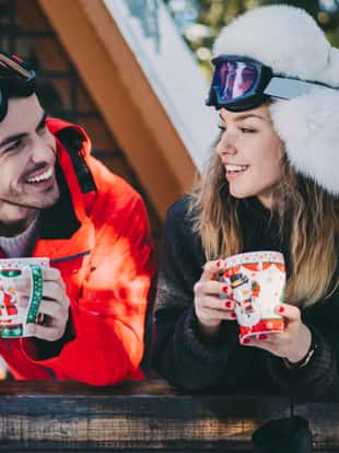 Young couple on winter holiday enjoying a cup of tea at the veranda