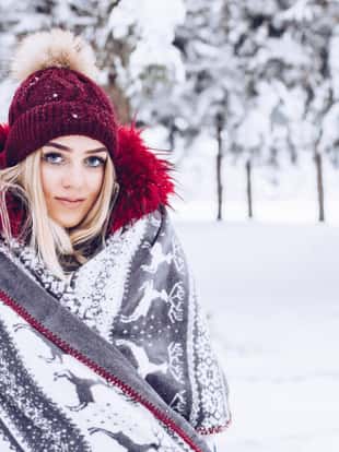 Snowy day, female hiker is enjoying her day in the nature, warm clothing and knitted hat