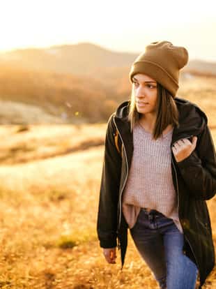 Hipster couple of hikers walking into beautiful nature on mountain in autumn with backpacks