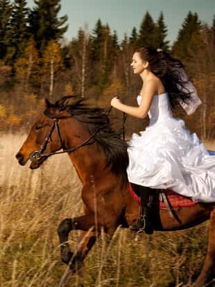 The bride in white dress riding on horse.