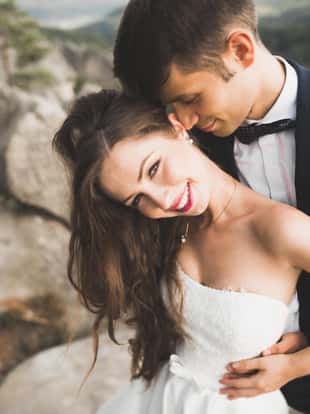 Wedding couple in love kissing and hugging near rocks on beautiful landscape.