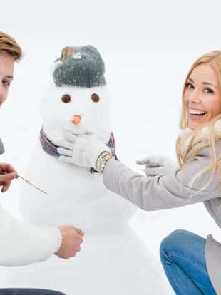 Beautiful smiling couple making snowman