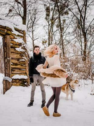 A drive couple dancing in a snowy park near their a dog
