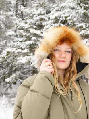 Beautiful young woman with furry hood in winter