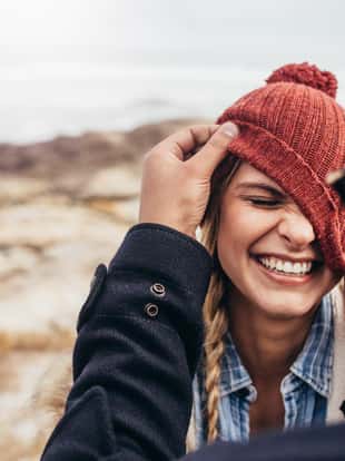 Close up portrait of smiling young couple having fun outdoors. Man and woman enjoying themselves on a winter day at the beach.