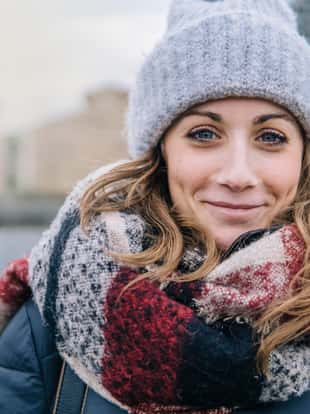 Close-up of young beautiful woman smiling outdoors in winter