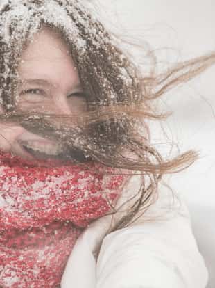 Teenager girl in the blue jacket and cape under snowfall at the street in Queens Village, New York City, NY, during the snowstorm Jonas