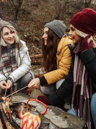 Three young female campers enjoying barbecuing chicken