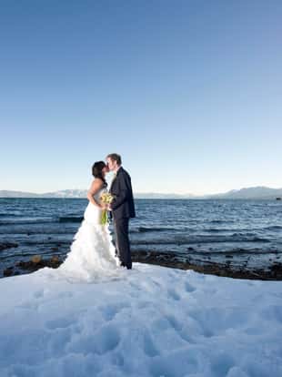 A bride and groom kissing in lake Tahoe on the snowy beach