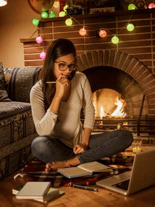 young woman studying at home sitting next to the fireplace,cozy ambient