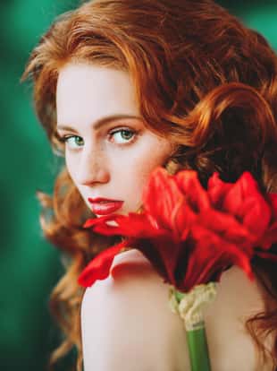 A close up portrait of a lovely beautiful girl with a big red flower. Beauty, cosmetics.