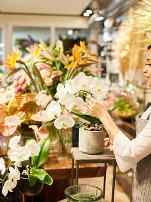 Asiatische Frau als Floristin dekoriert Blumengebinde im Blumenladen
