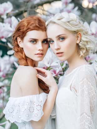 Beautiful girls in the rays of sunset light on the background of spring bush