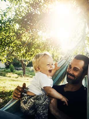 Shot of a father holding his baby boy while relaxing in a hammock