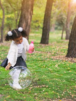 Little girl playing with soap bubbles in the park