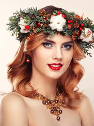 Portrait of beautiful young woman with Christmas wreath. Beautiful New Year and Christmas tree holiday hairstyle and makeup. Beauty girl portrait isolated on white background. Colorful makeup and hair