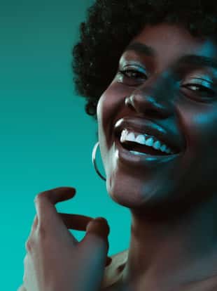 Deep ocean. Portrait of female fashion model in neon light on gradient background. Beautiful african woman with trendy make-up and well-kept skin. Vivid style, beauty, cosmetics concept.